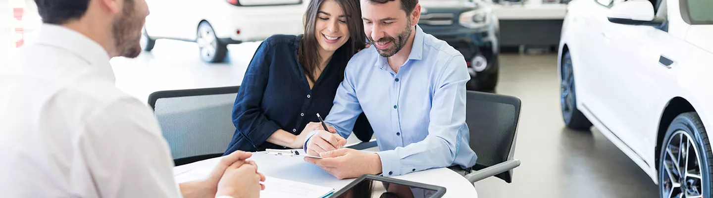 Customers sit and sign paperwork for a used Toyota