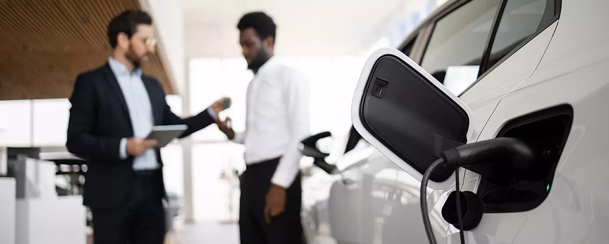 EV charging in the show room with a deal being made in the background