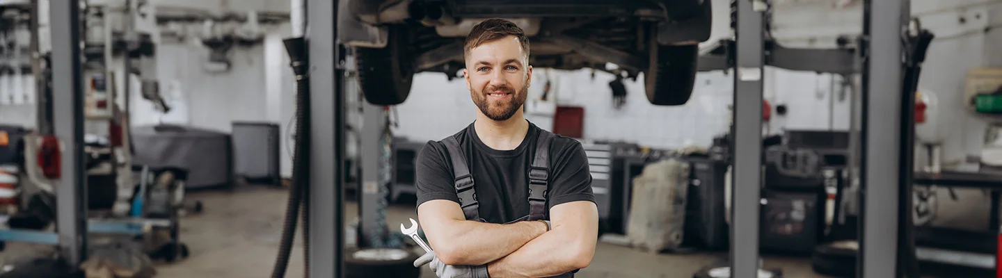 mechanic in garage smiling for camera