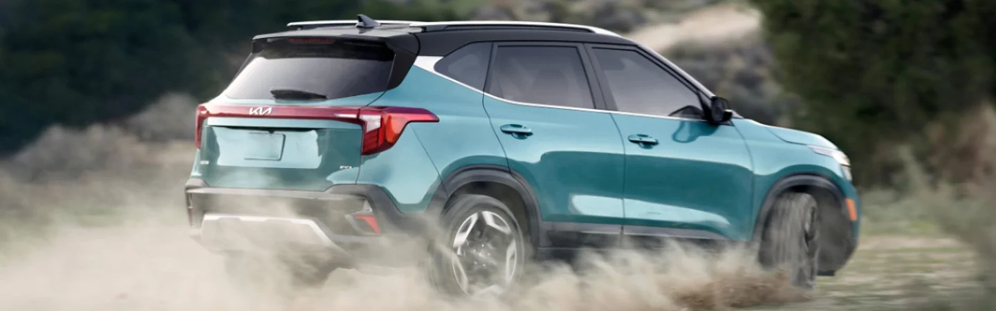 Kia Seltos driving kicking up dust rear view