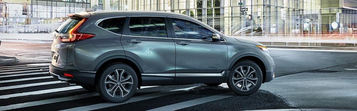 Blue Honda CR-V driving in city passenger side view
