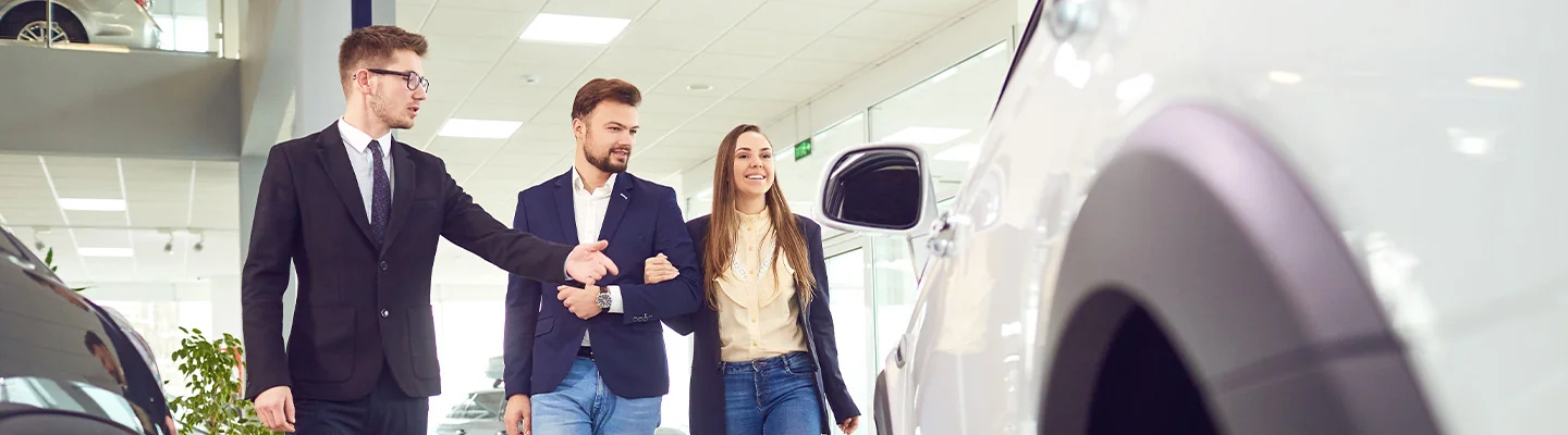 couple in deaerlship discussing car purchase with sales person