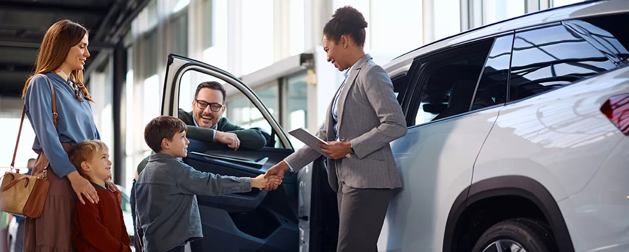 Family talking to a car salesman at a car dealership