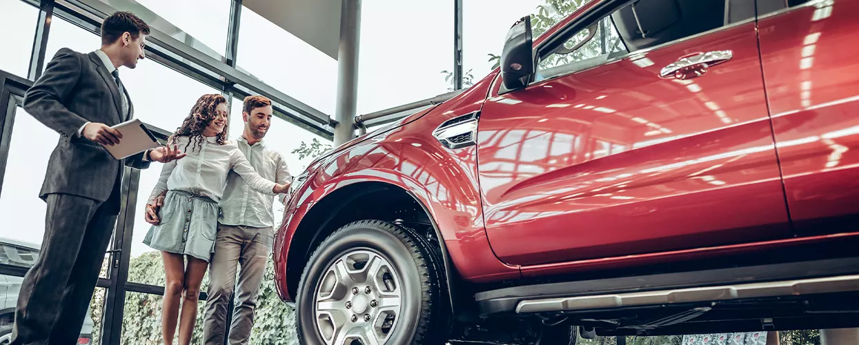 Car salesman showing a couple a new vehicle