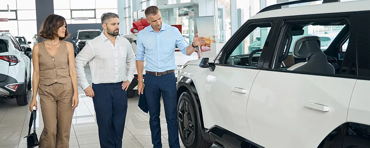 Couple talking to a car salesman at a car dealership