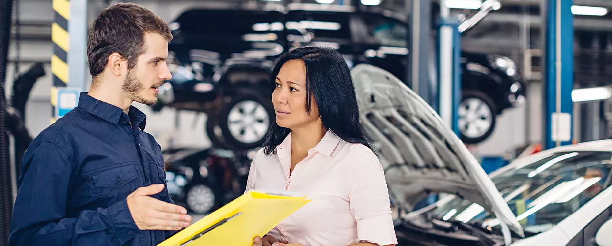 Service mechanic talking to a customer at a service bay