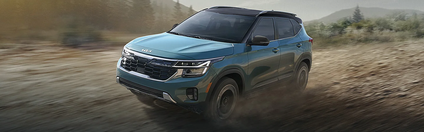 Front side view of a 2025 Kia Seltos driving though dirt