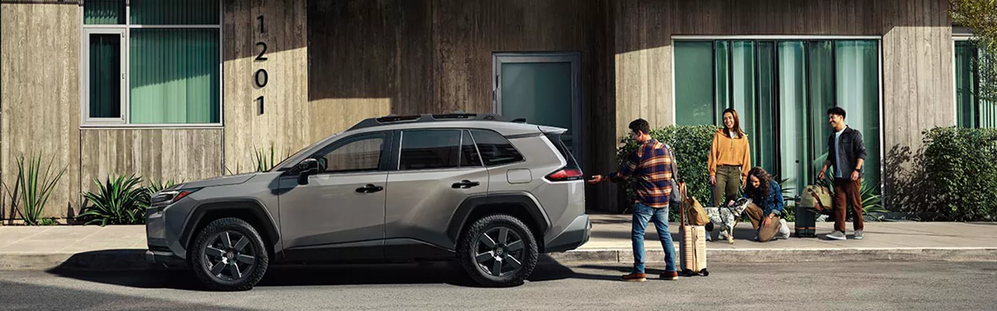 2026 Toyota RAV4 parked in front of a building with people loading things into it in Holiday, FL
