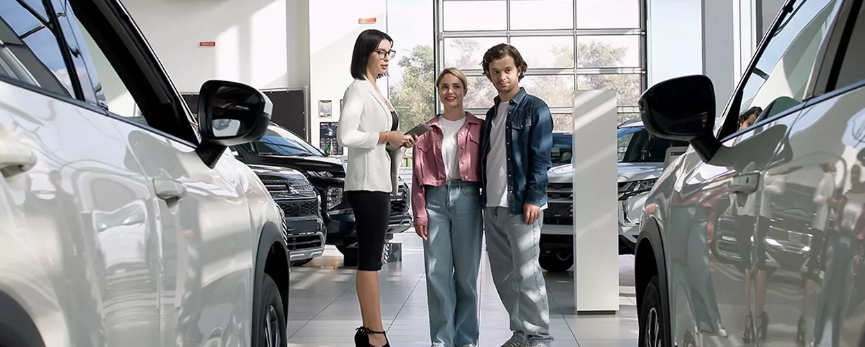 Car salesman showing a couple a new vehicle at a car dealership