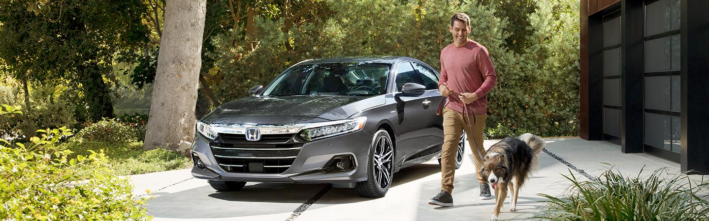 2021 Honda Accord parked in a drive way next to a man taking his dog for a walk