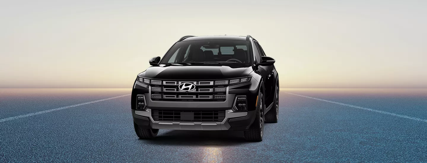 Front view of 2026 Hyundai Santa Cruz parked in a parking lot with the sunset in the background