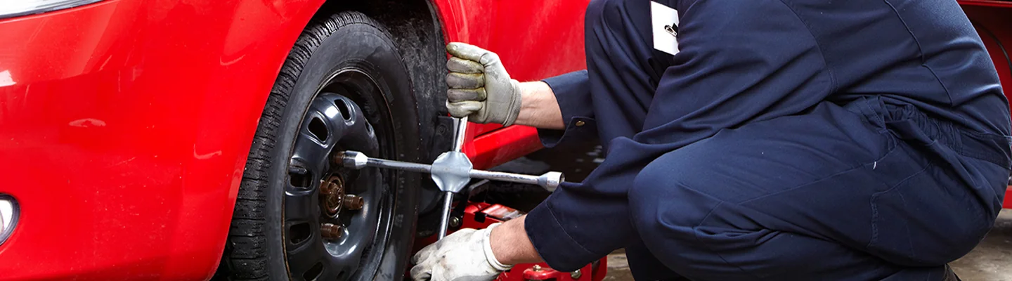 Service tech changing a wheel on a a car