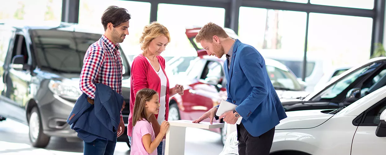 Car salesman talking to a family about a new vehicle
