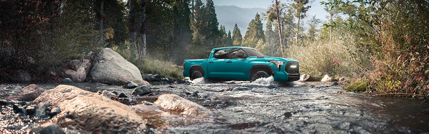 Side view of 2026 Toyota Tundra driving across a creek