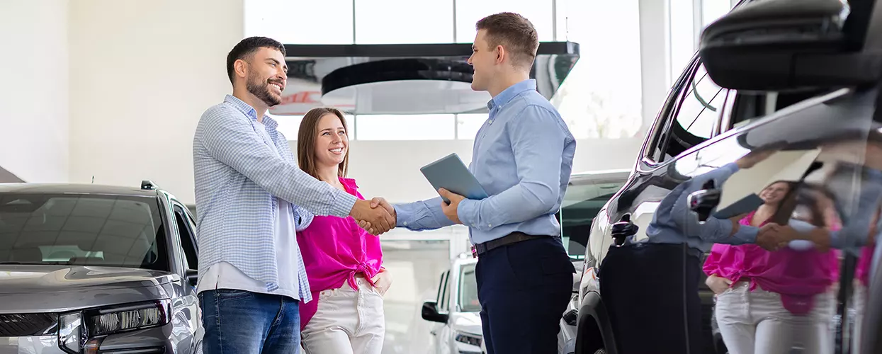 Car salesman showing a couple a new vehicle