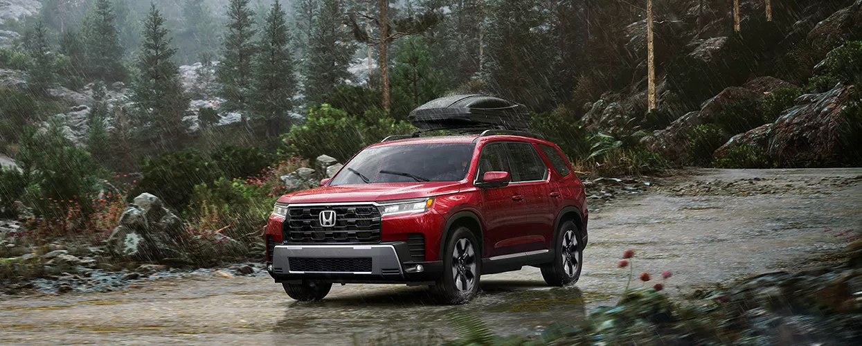 Honda vehicle driving on a dirt path in the forest