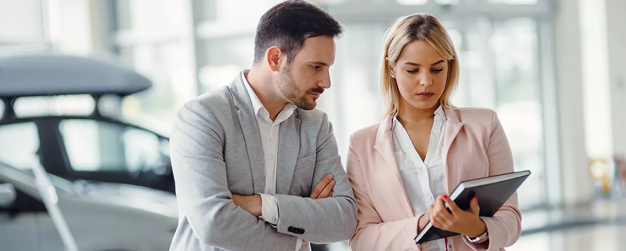 two people going over details of a car purchase on a tablet