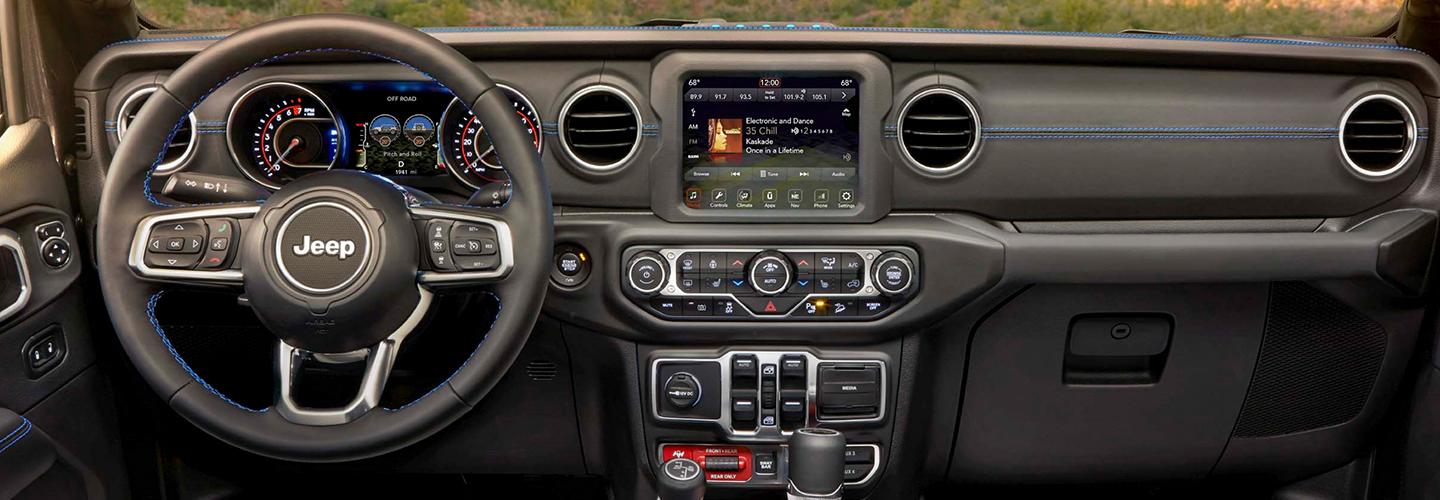 View of the steering wheel and infotainment system of a Jeep Wrangler.