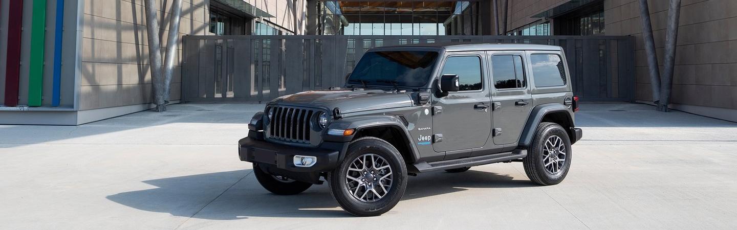 Front view of a grey Jeep Wrangler parked near some buildings.