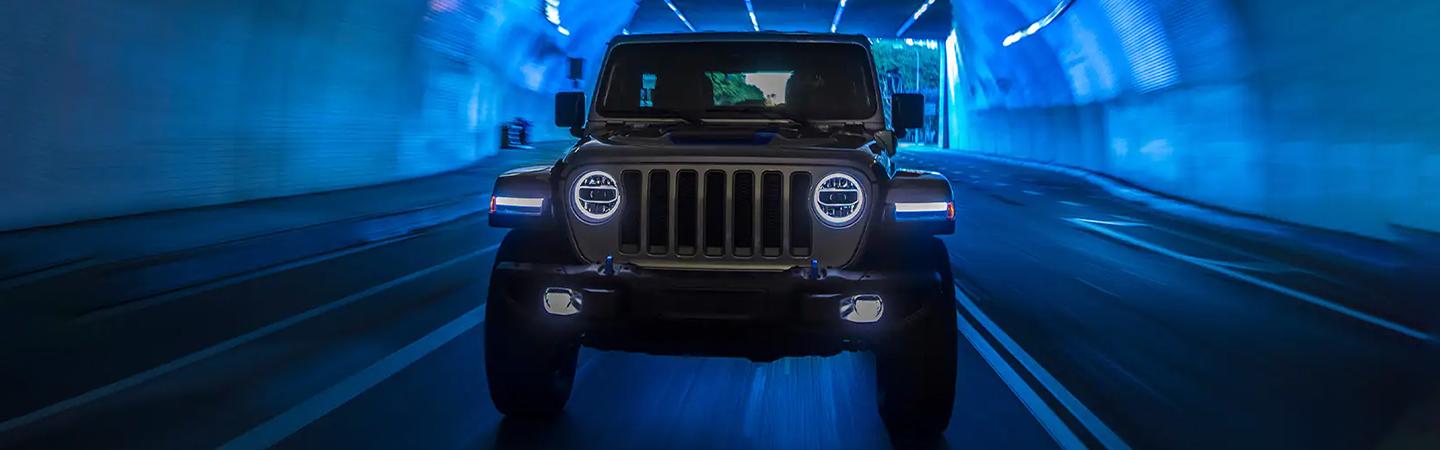 Front view of a grey Jeep Wrangler driving through a tunnel.