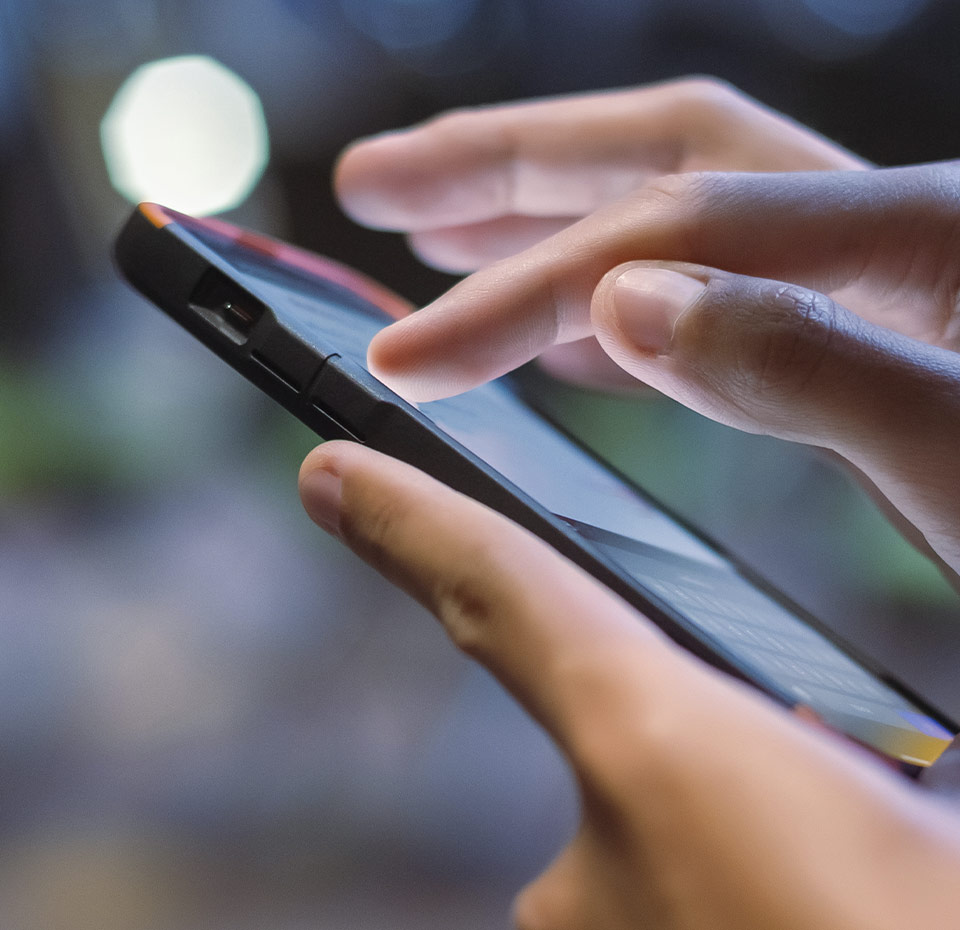index finger touching a smart device screen with the other hand holding it