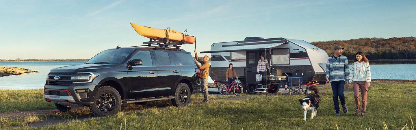 2023 Ford Expedition parked at a lake with family, RV and kayak on the roof
