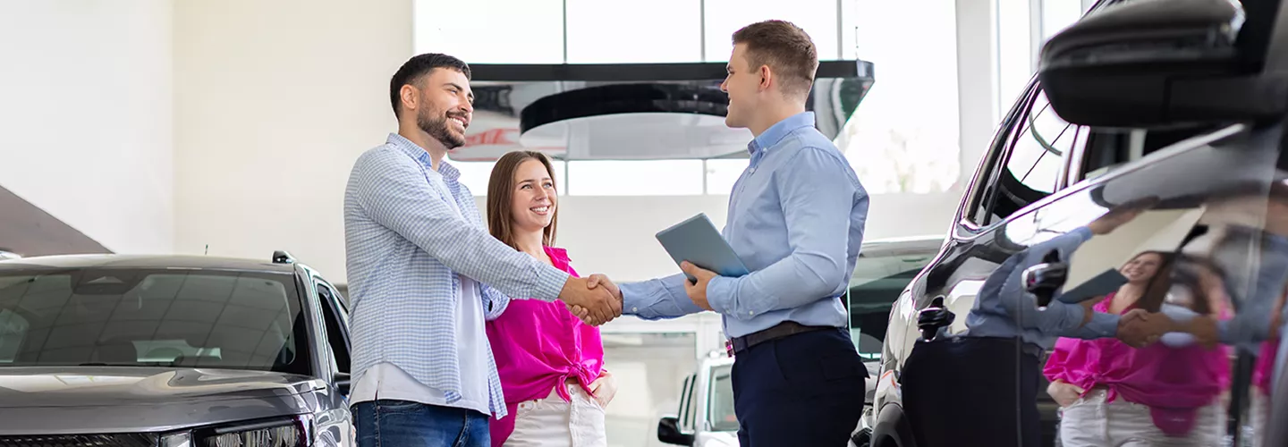 shaking hands with a customer in car showroom