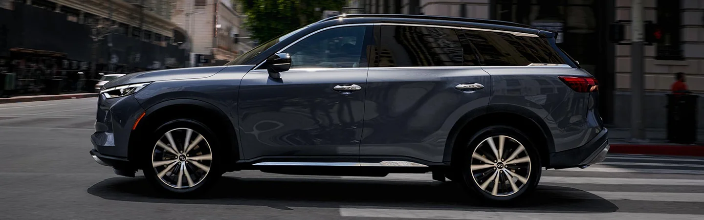 Side view of a 2023 INFINITI QX60 driving in the city