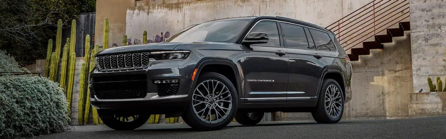 black 2021 Grand Cherokee L parked by building with cactus, stairs and wall