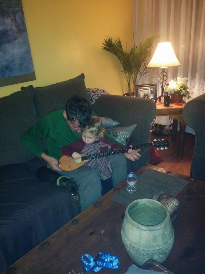 Grandpa teaching grandson how to play bouzouki.