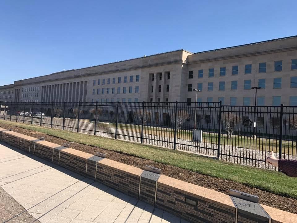 The Pentagon in the background. The metal plaques are years and a line stretches from one side to the other. The structures are lined up in the row that corresponds to their date of birth.