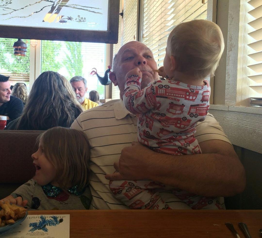 Jack trying to "share" a slimy French fry with his uncooperative grandpa.