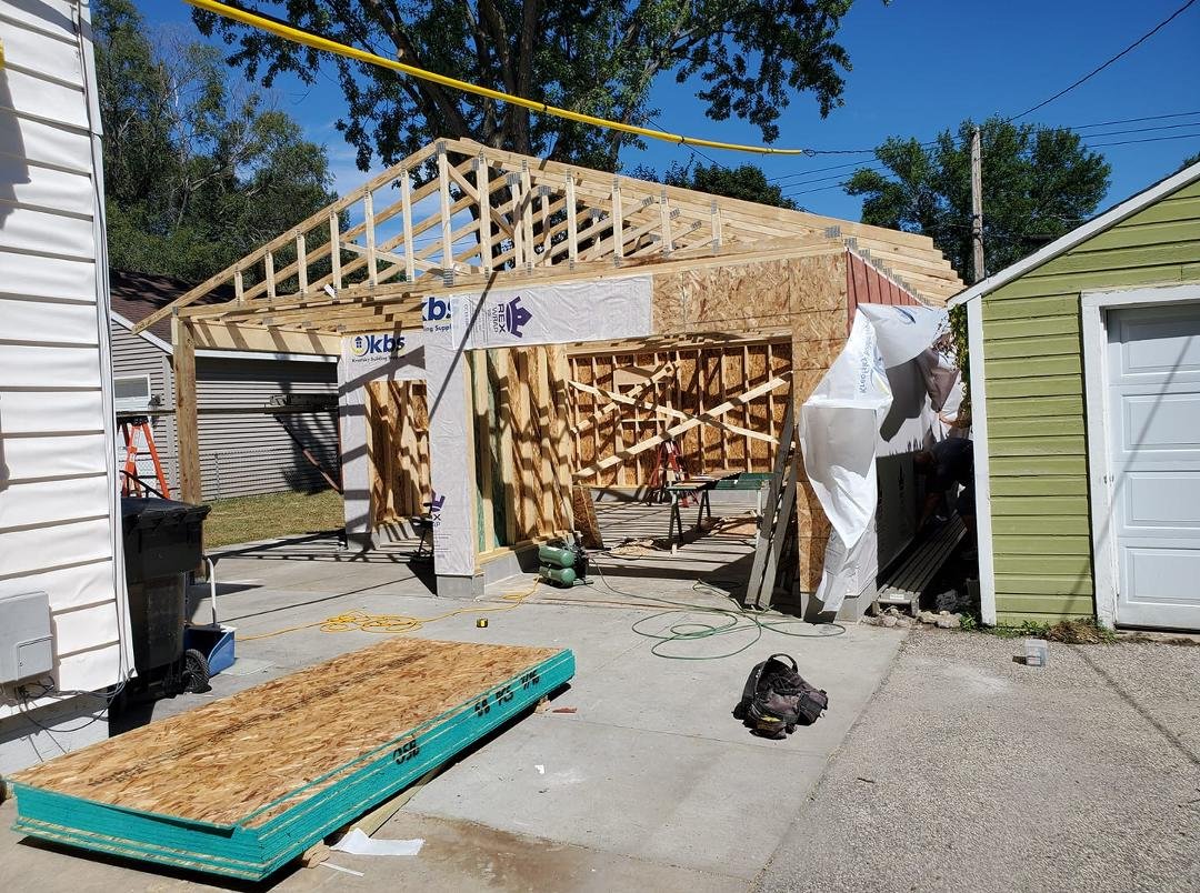 Looking more like a garage and workshop today!  Trusses installed,  wall paneling all around and wrapped.   The side facing my neighbor's garage is sheetrocked with fire resistant panels over that.   New codes require it.  