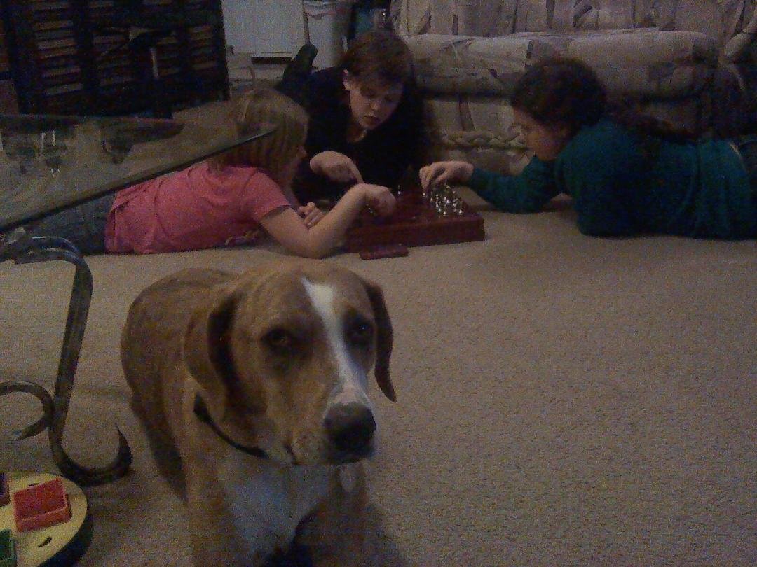 Emma helping Peggy help her friend play chess.