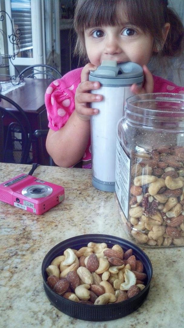 Nana pours some nuts in the lid for Noelle...
Noelle pushes lid to Nana and takes container.  "This is for you and this is for me!"