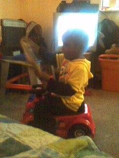 PATRICK IS SITTING ON HIS CAR & READING 1 OF HIS COLORING BOOKS!