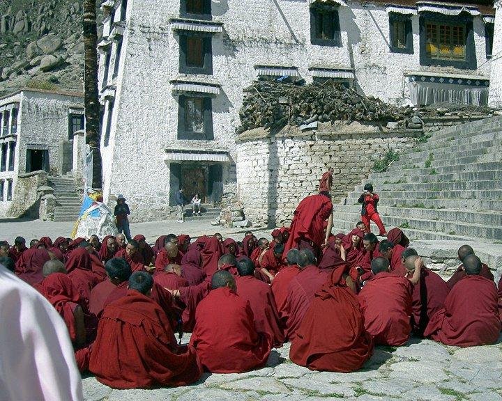 A bunch of Monks watching their amigo absolutely rip the two that are hanging their heads... they call it a "debate".