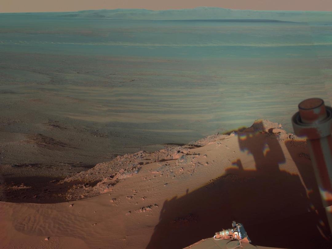 The Mars rover, Opportunity, snapped this color photo as it rolled up to the Endeavour crater. Note that you can see the rover's shadow, and if you look in the distance, what appears to be hills is actually the other side