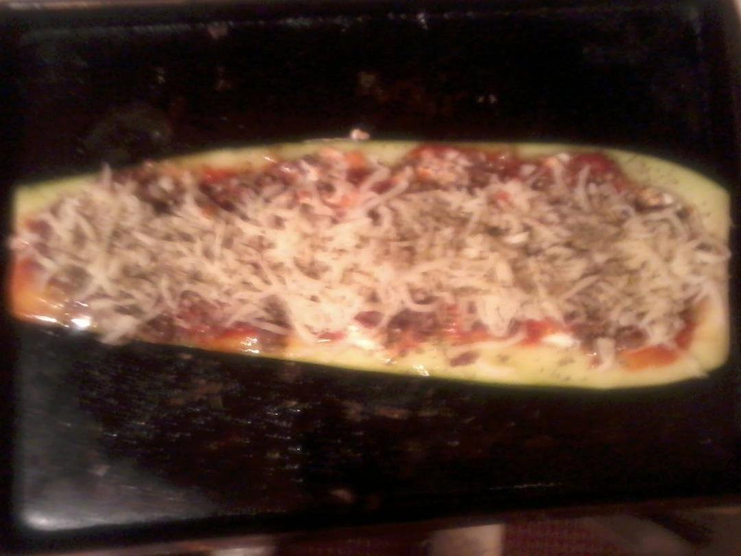 What can one do with those giant zucchinis at harvest time? Try this, a dieter's haven of pizza/lasagna get over it lust! Get a huge zucchini and slice it in half. Scrape out the innards. Brown one pound of 90% lean beef or