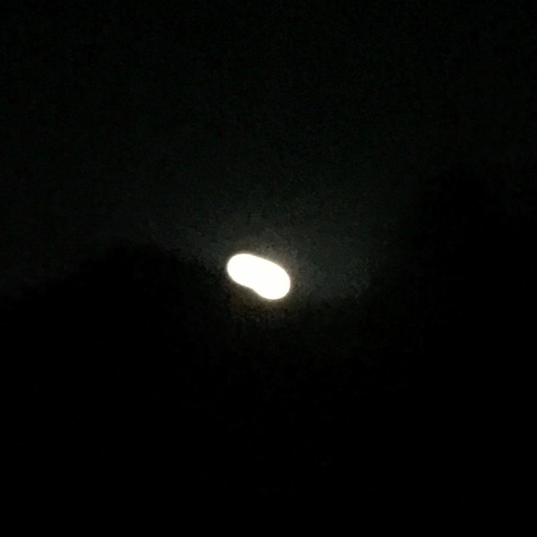 “The Special Giant Moon” over a dirt parking lot or a button over the same parking lot.
