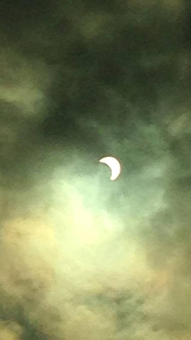 I took this picture of the eclipse today, with my iPhone 5 through the clouds with my sunglasses over the camera lens.