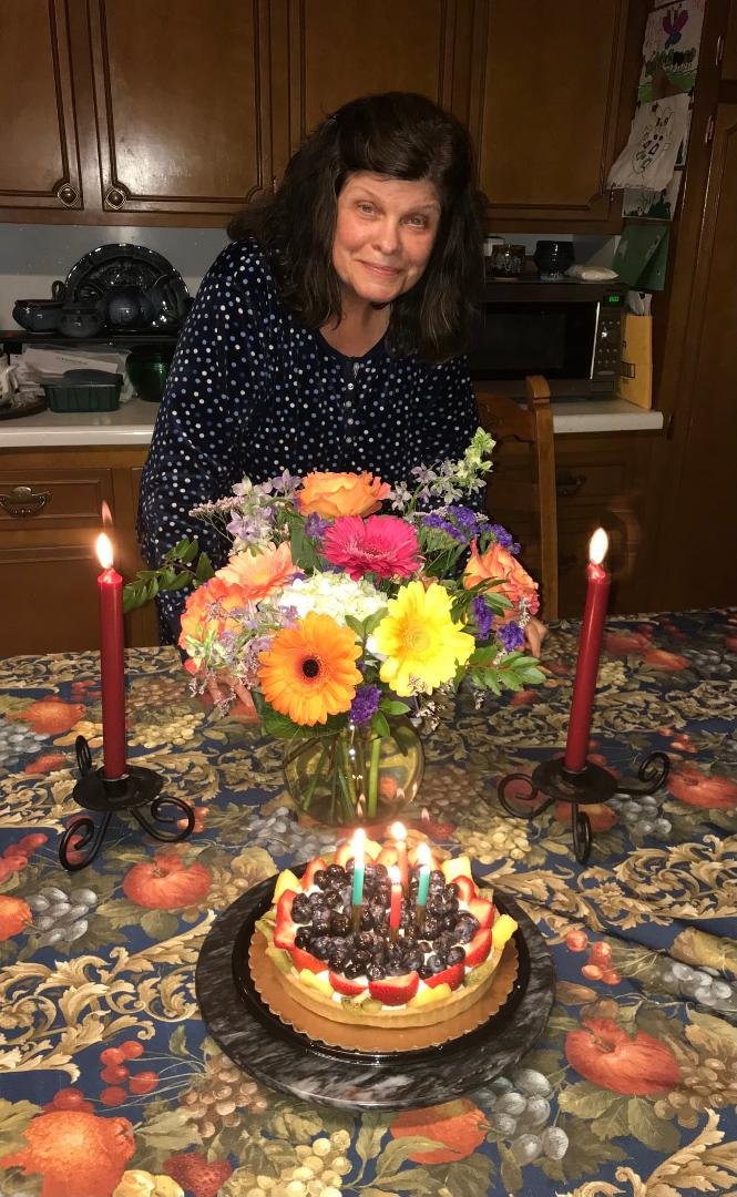 Pamela Jayne Wills poses with her birthday flowers and fruit tort in the kitchen of our home.