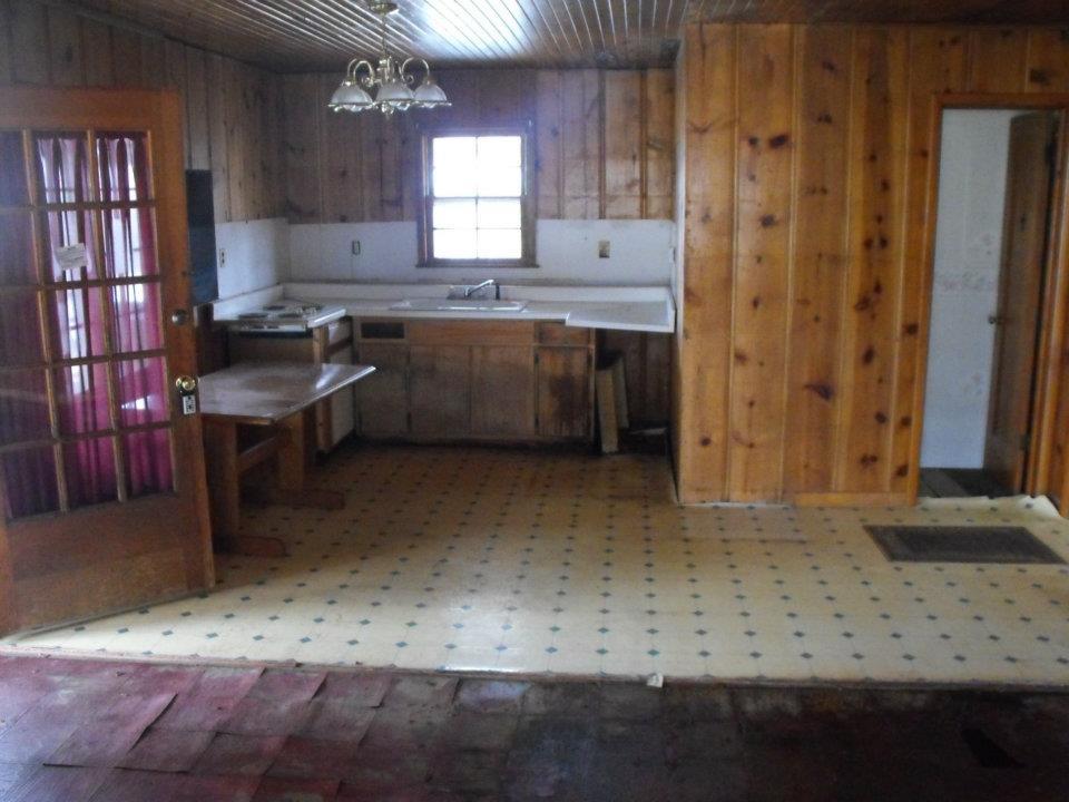 Kitchen. The counter top and cabinets were not even attached to the wall when we bought it, and that is a floor furnace to the right, in front of the bathroom door.