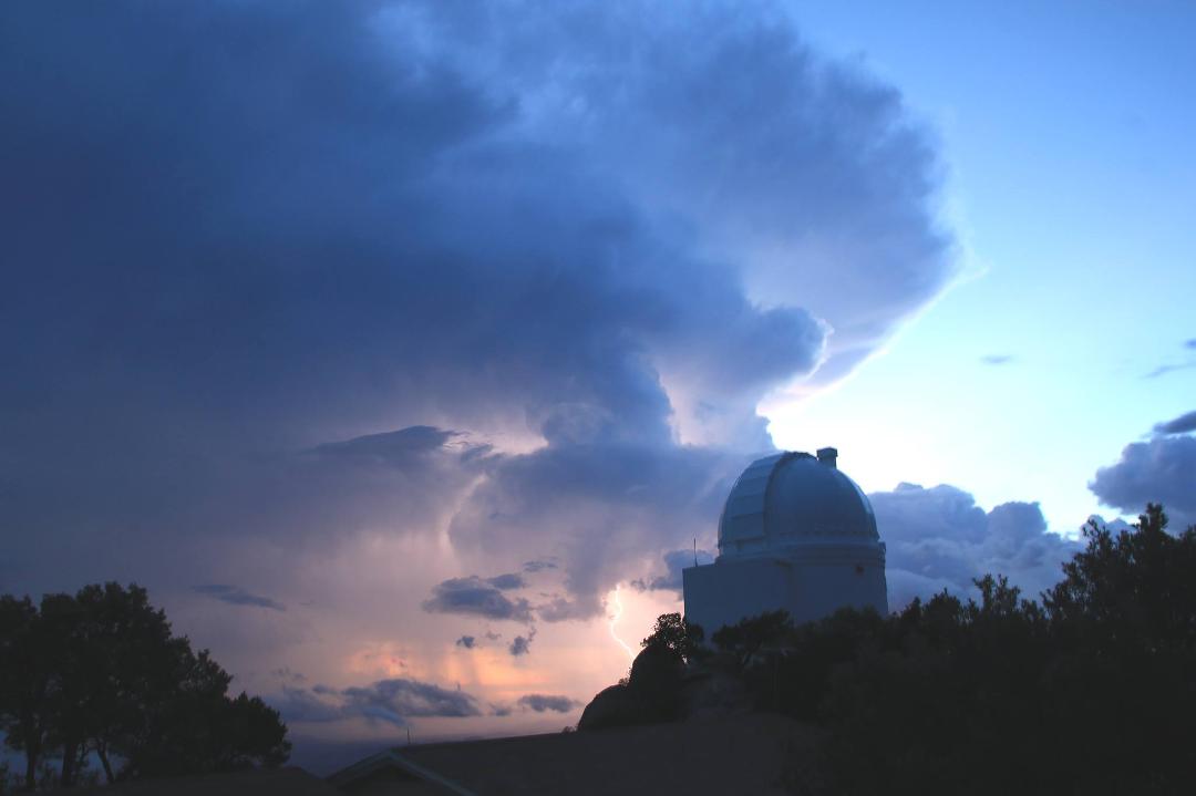 A lightning strike in the valley behind the dome with rain all around as well.