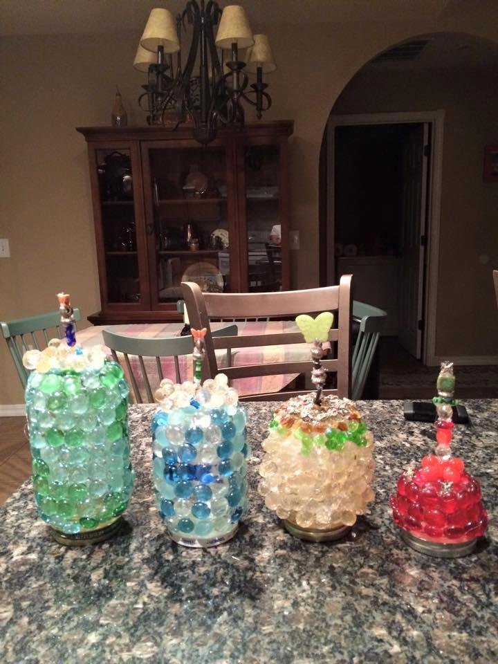 I made these, they are glass jars with lids that I decorated with glass beads and whatever else suited my fancy. Screw the lids on upside down onto garden stakes and pound into the ground. Screw the decorated jars onto th