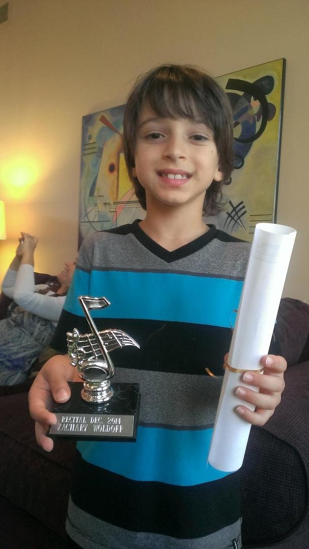 Proud Zachary gets a trophy for his piano recital.