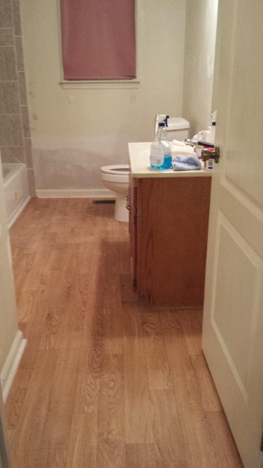 The tiled shower is on the left at the end. We have not painted yet or put up a new light above the vanity, but the vinyl on the floor looks like real oak. Got the vinyl at Home Depot. Tub, toilet and tiles at lowes.