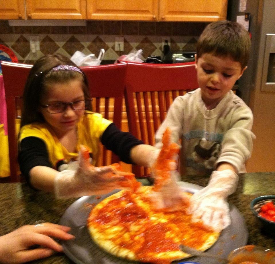 Spreading the sauce, then adding the cheese and vegetables.