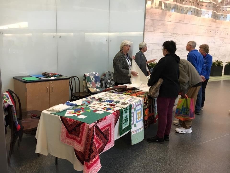 A lady demonstrating Quilt making.