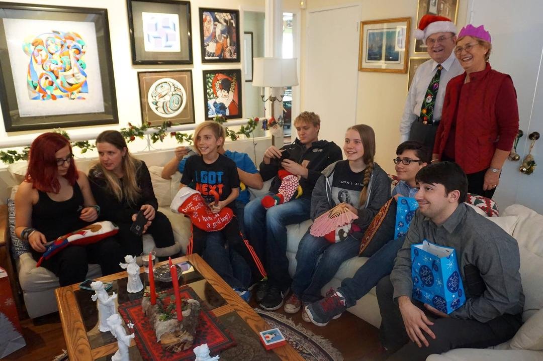 Grandchildren opening stockings and gifts around fireplace.